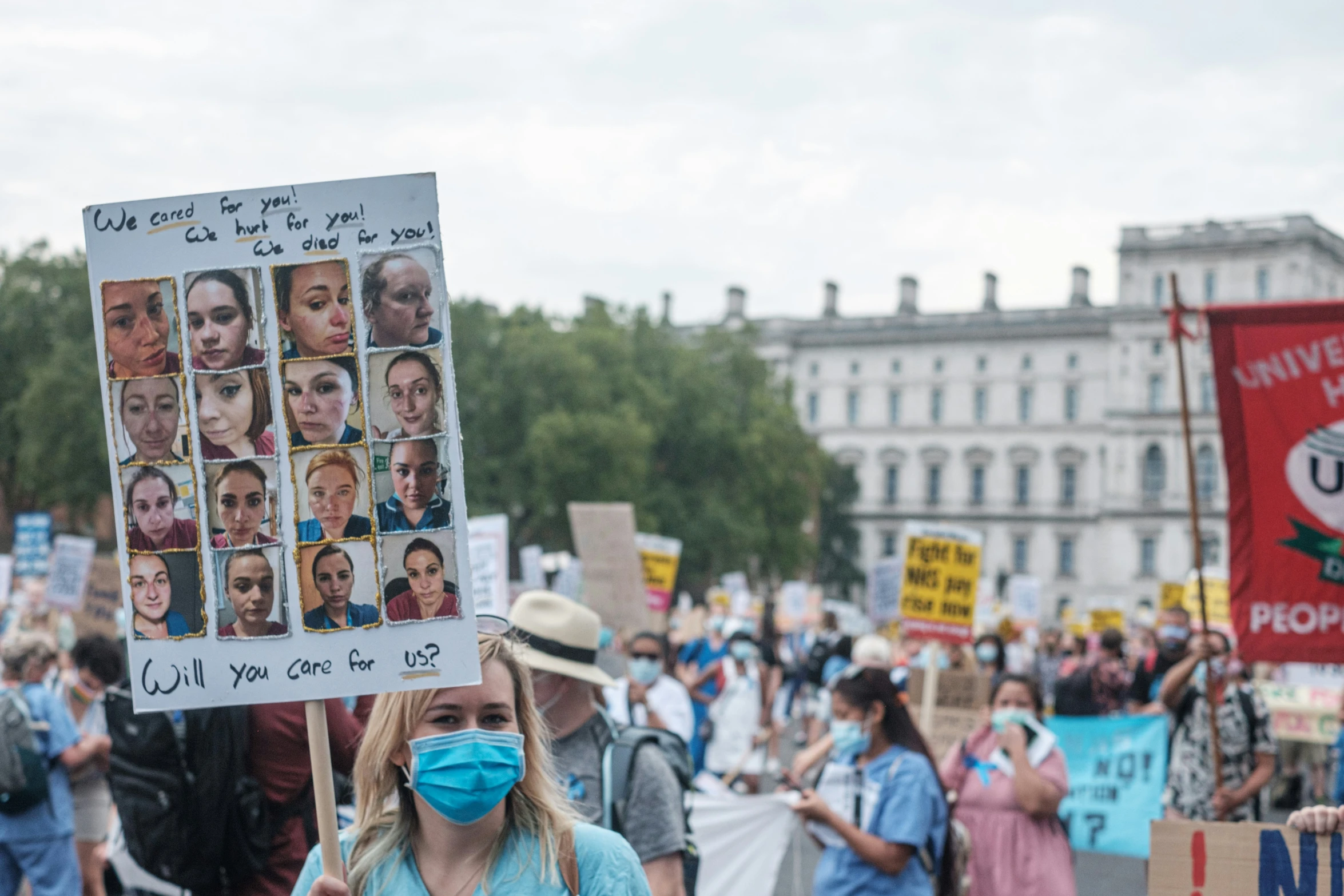 a woman holding a protest sign with pos of people on it