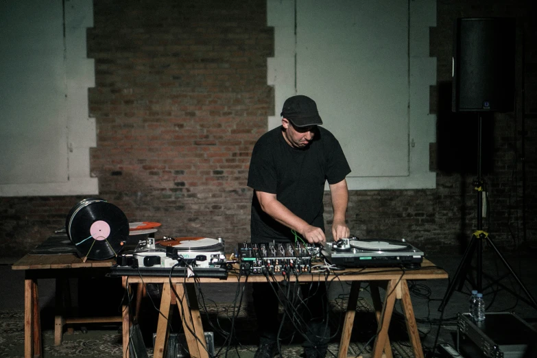 a dj mixing music in front of an old brick wall