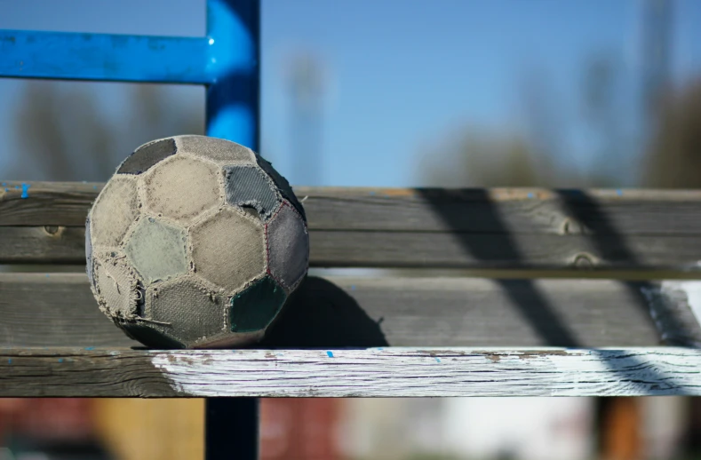 an old, dirty soccer ball sitting on a park bench