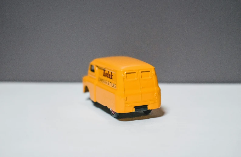 the yellow toy truck sits in front of a gray background