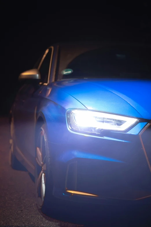 a bright blue car that is driving in the dark