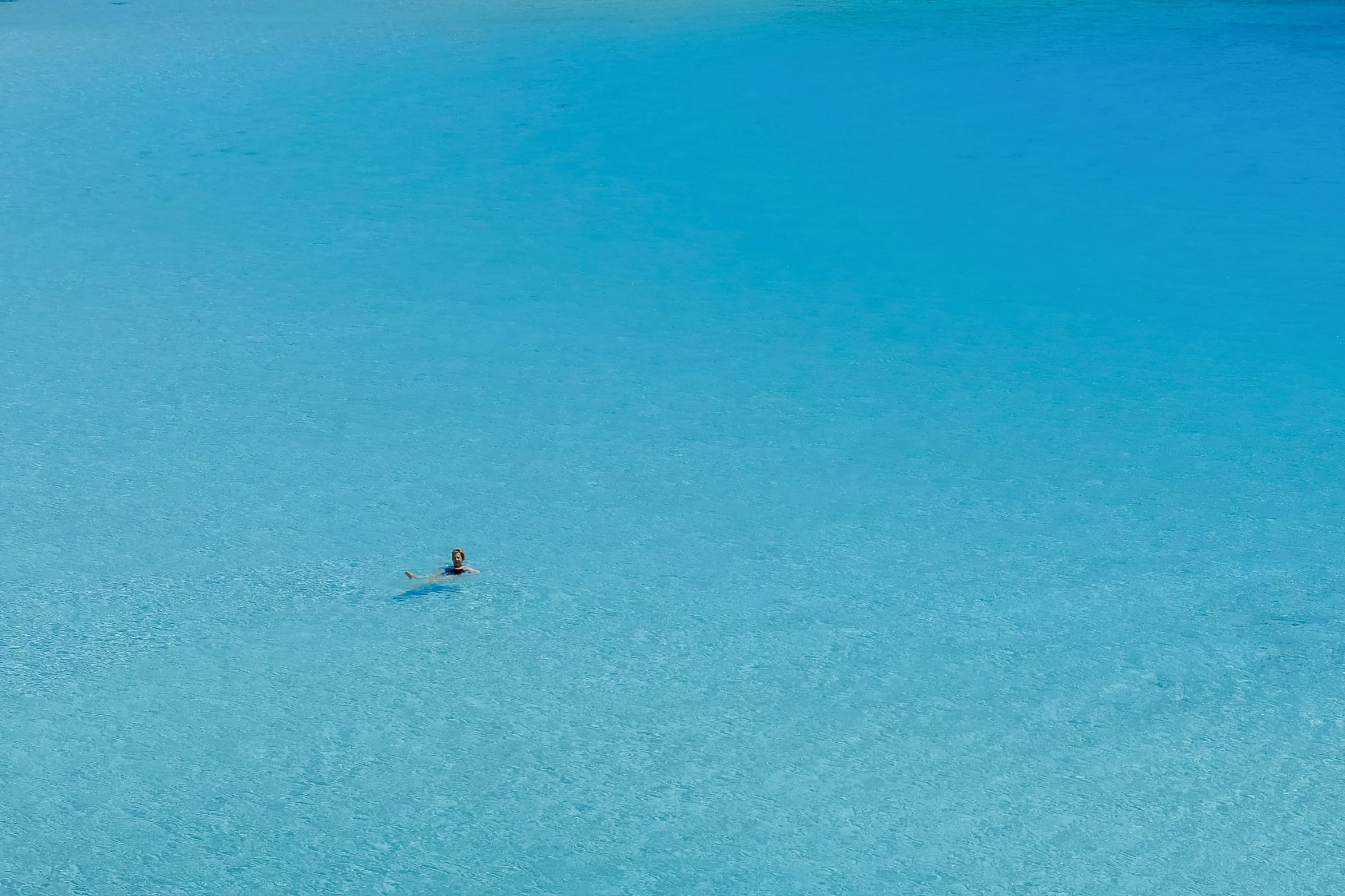 a lone surfer is surfing a wave in a blue lagoon