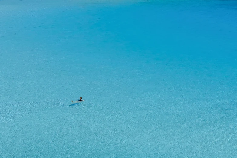 a lone surfer is surfing a wave in a blue lagoon