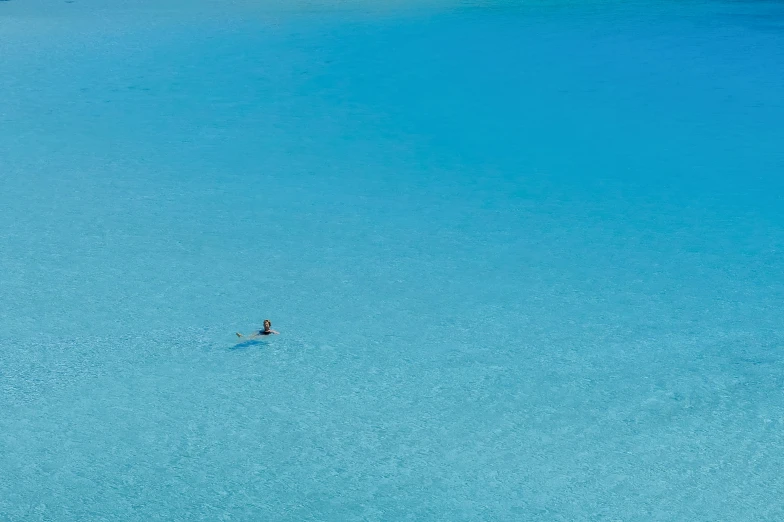 a lone surfer is surfing a wave in a blue lagoon
