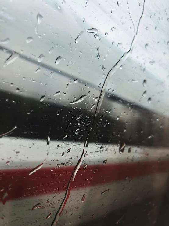 rain is sitting on the window next to a train