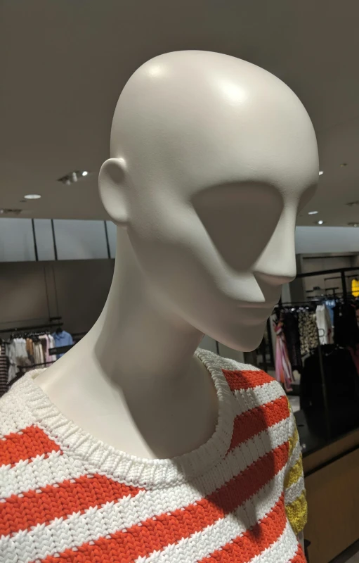 a close up of a mannequin with clothes behind it