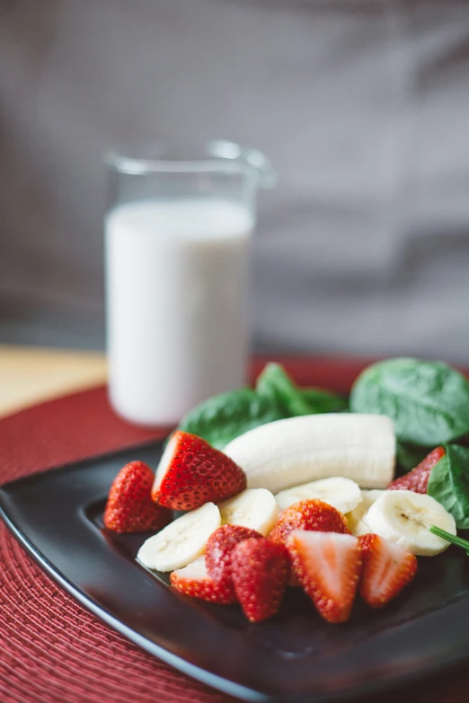 a plate with strawberries and bananas and a glass of milk