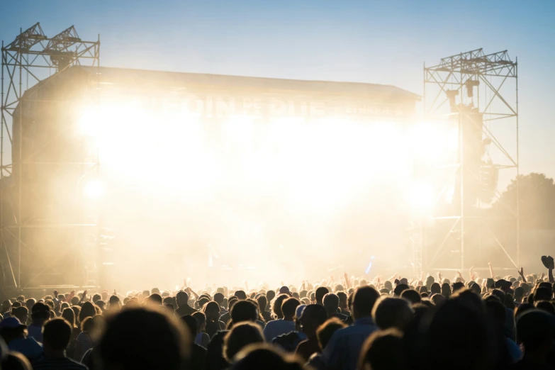 a concert stage with bright beams and the crowd in the foreground