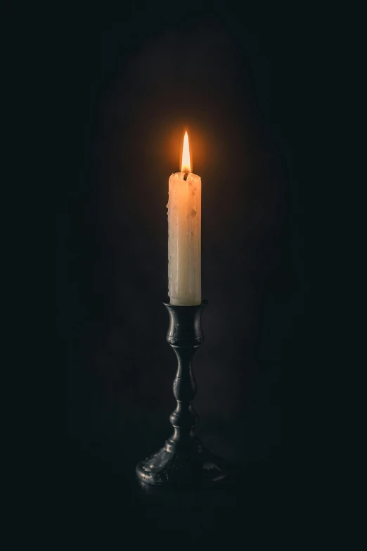 a single light burning from a candle on a black surface