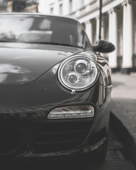 the porsche is parked on the curb near the building