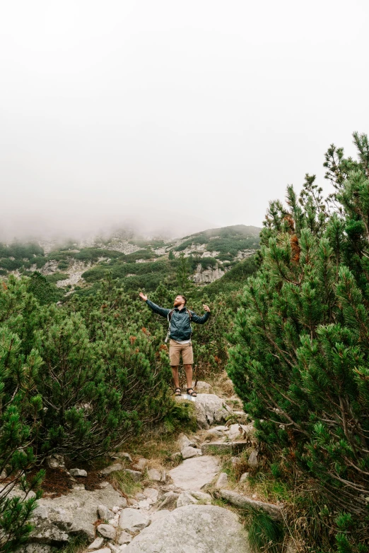 a man on top of a rock hill on a cloudy day