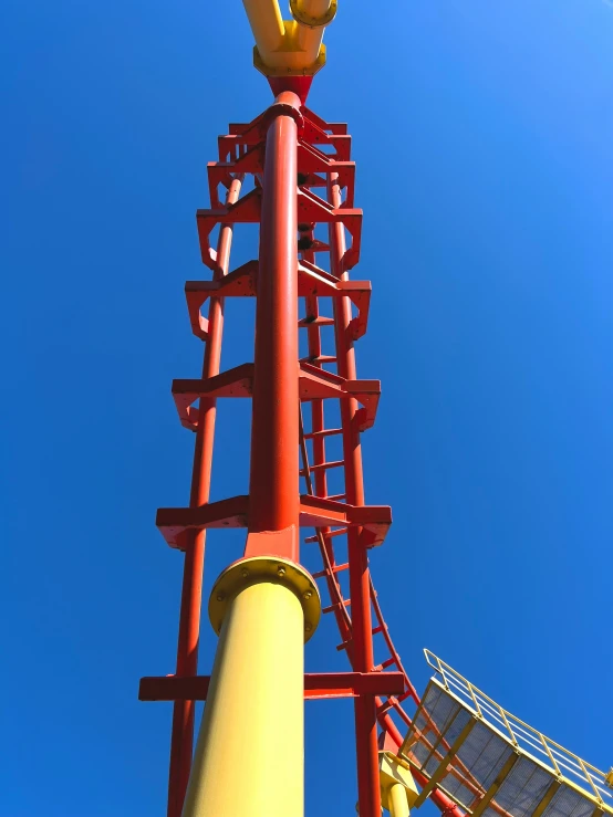 a yellow bird is perched atop a red pole