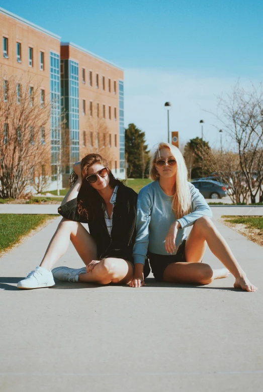 a pair of young ladies sitting on the ground