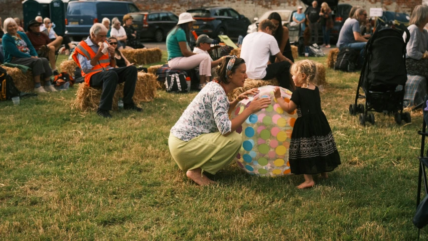 people sitting on the grass by a large crowd