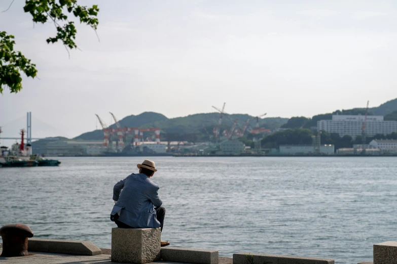 a person sitting by the water on a stone