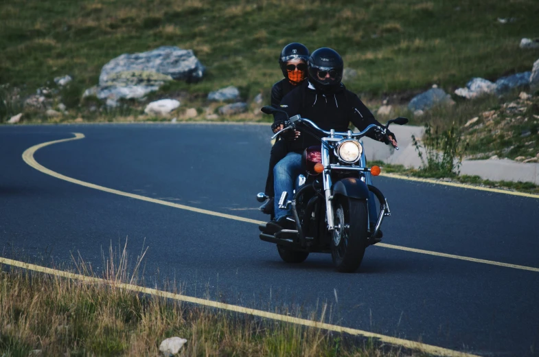 two people are riding motorcycles on the street