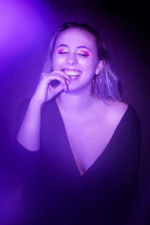 woman with purple eyeshadow and glowing makeup smiling