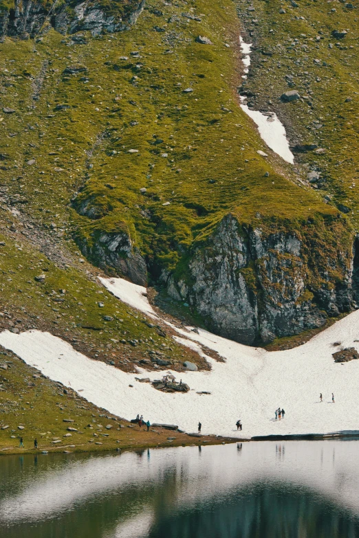 a snowy mountain in the foreground with lake below and mountains in the background