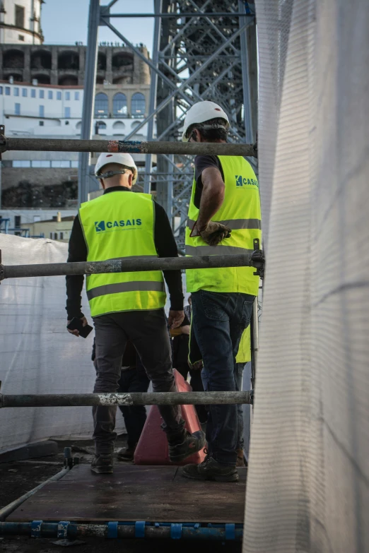 three construction workers dressed in safety vests talking on a dock