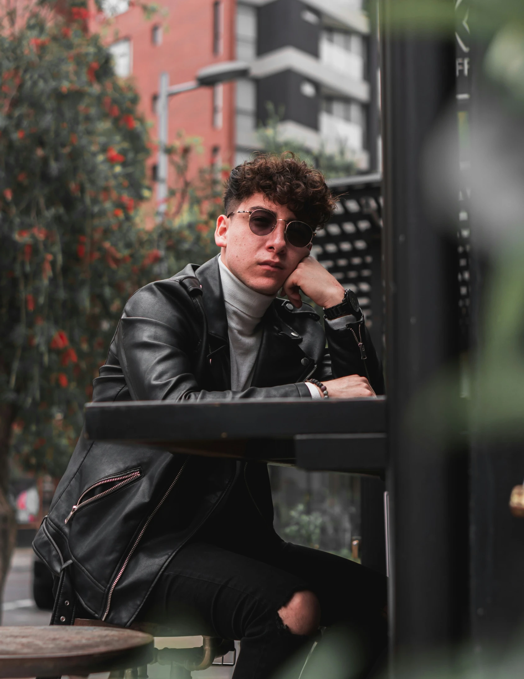 a man wearing black sitting on a metal pole outside