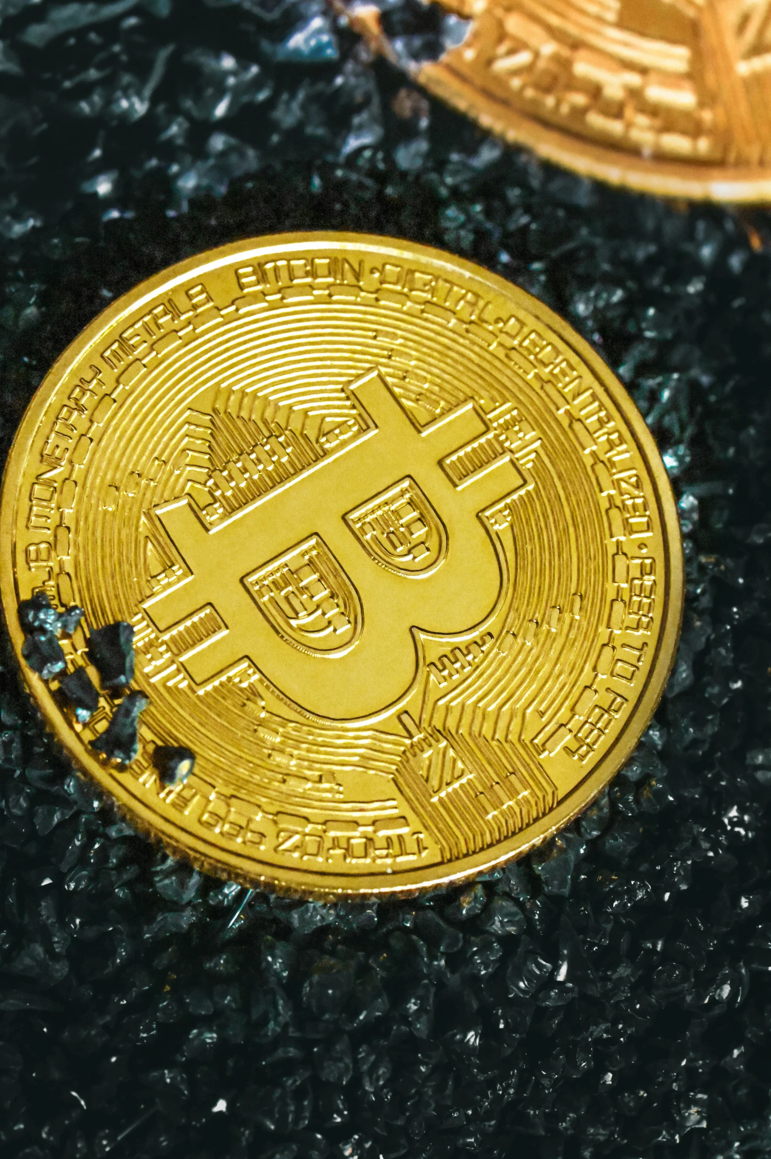 a gold bit coin sitting on top of a black surface