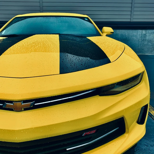 the front end of a yellow muscle car in a garage