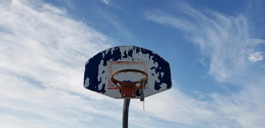 a basketball hoop with the rim almost up against a cloudy sky