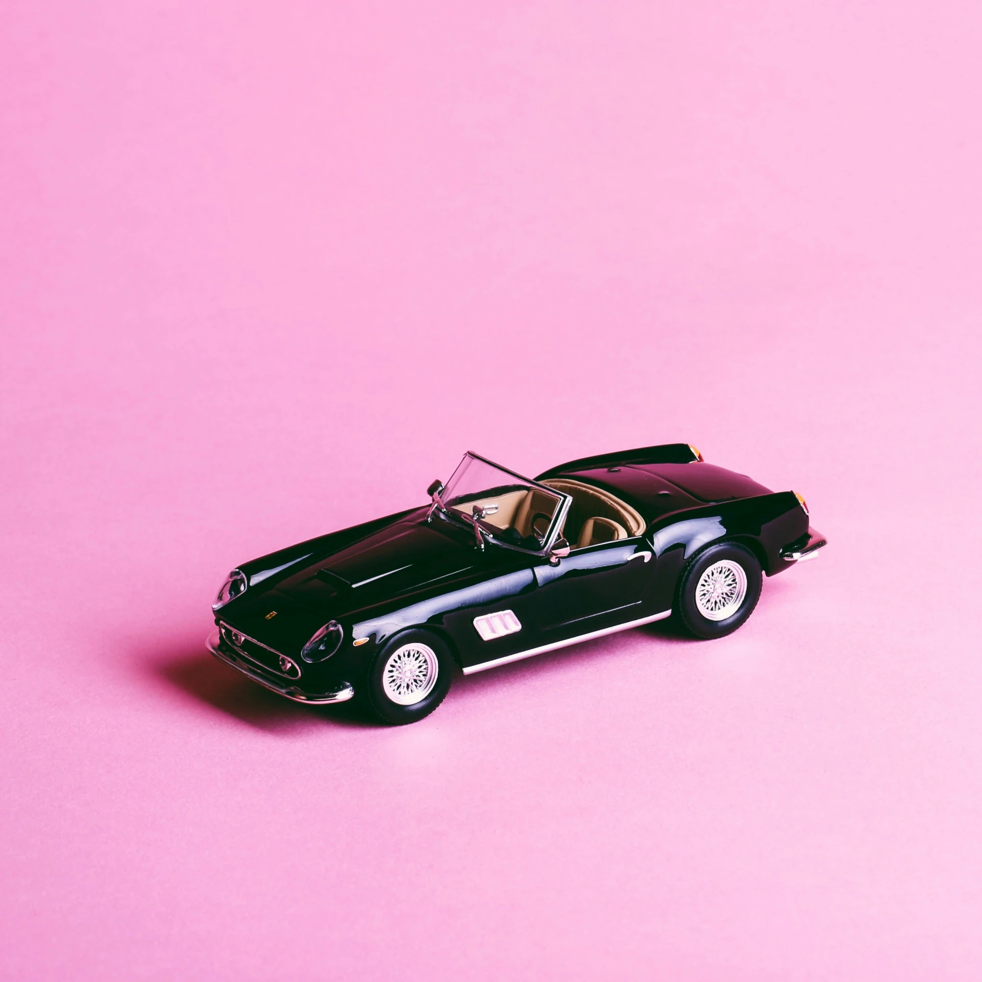 a model car sitting on top of a pink surface