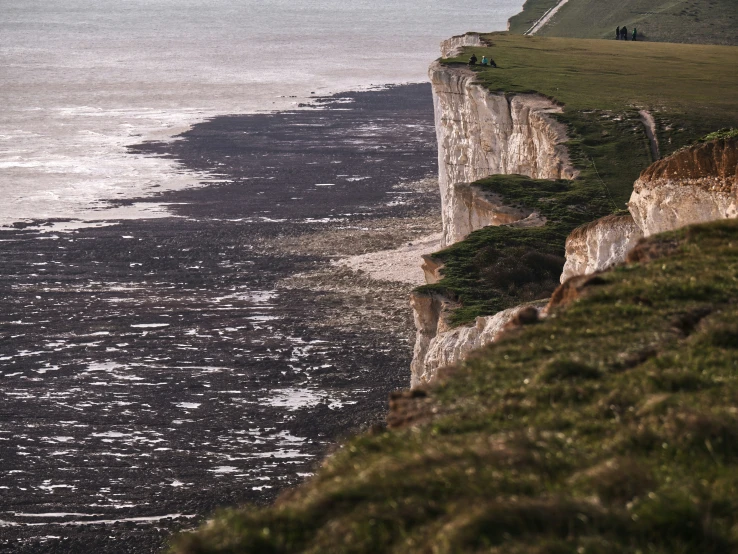 a cliff side near the sea with waves coming in to it