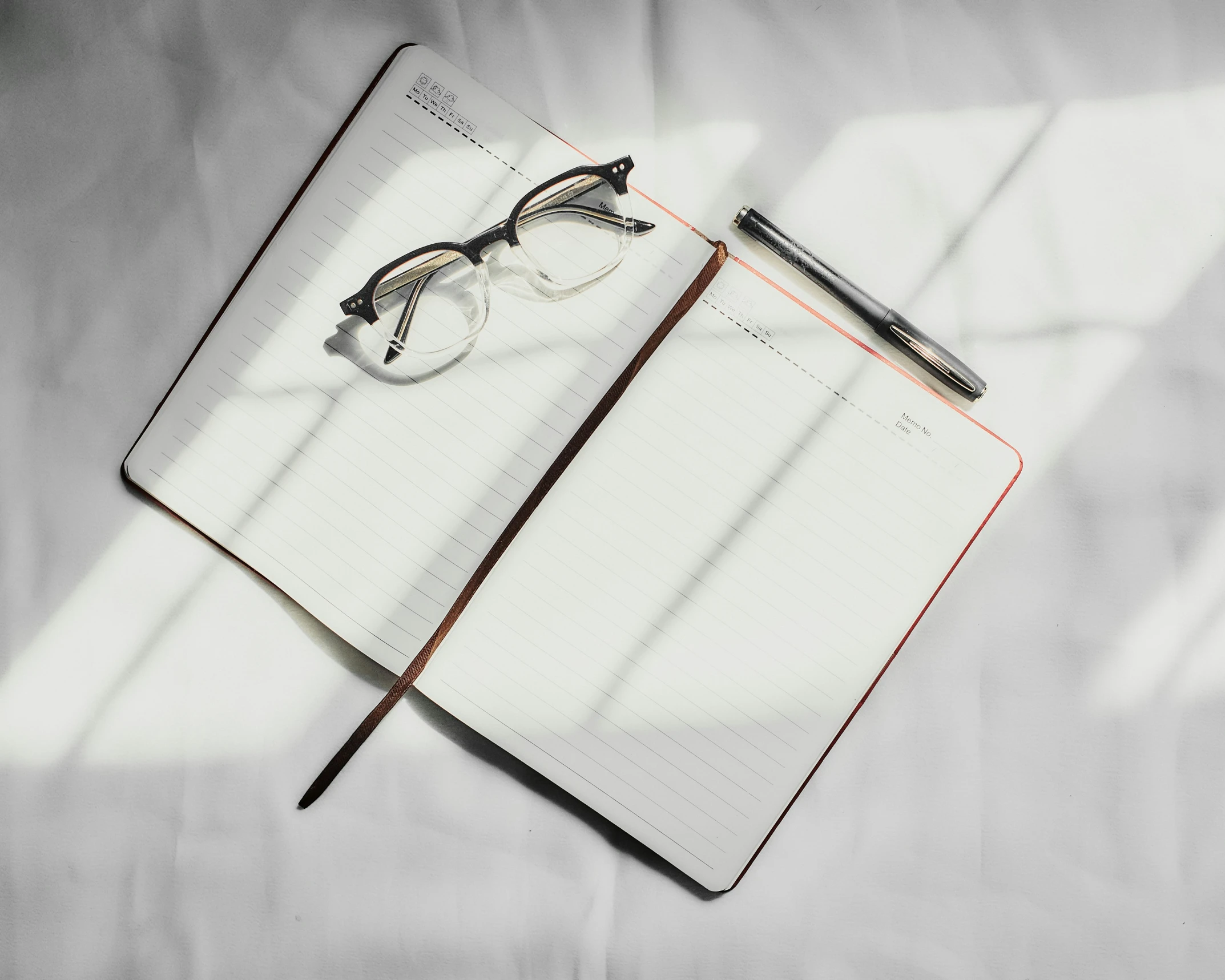 a notebook and a pen on a white sheet