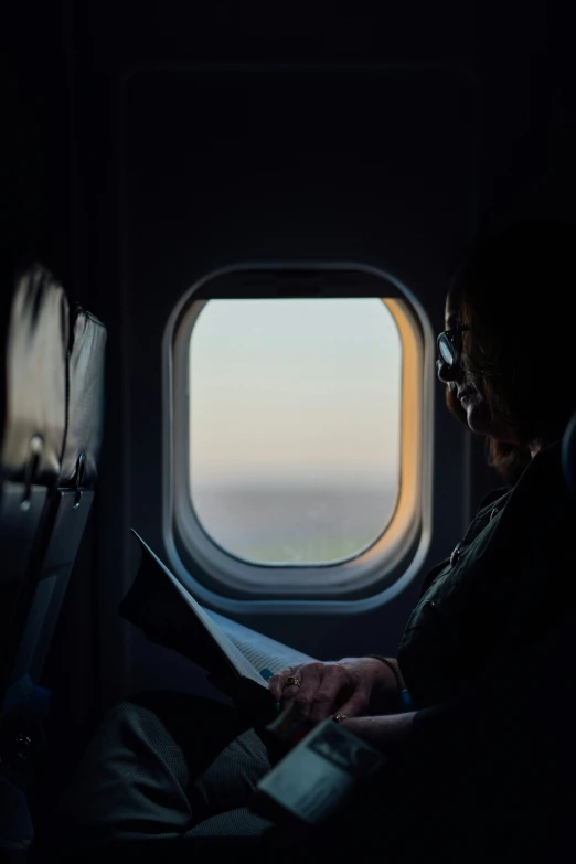 man looking at a tablet and writing on an airplane window