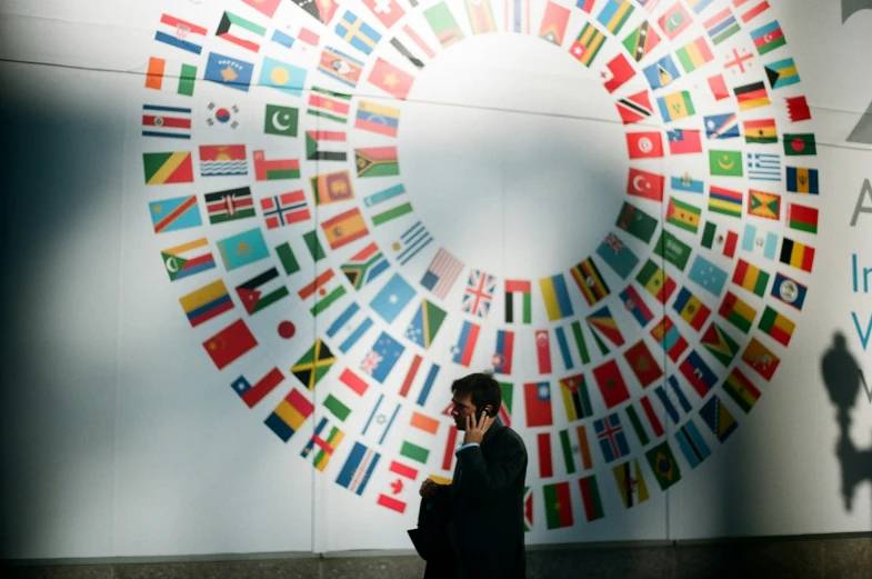 a woman talking on her phone and a wall decorated with flags