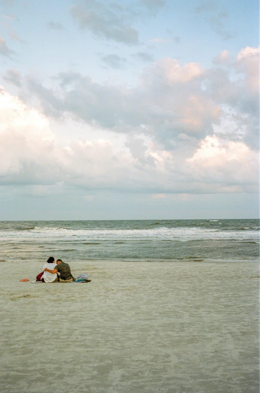 a man kneeling on a beach next to a kite