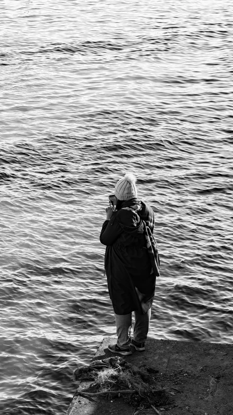 an old man is standing on the edge of a dock looking at water