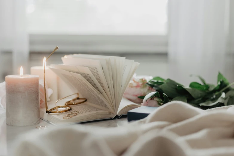 a book and candle sit next to each other on a bed