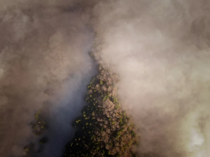 the very top of a hill is obscured by a cloud filled sky