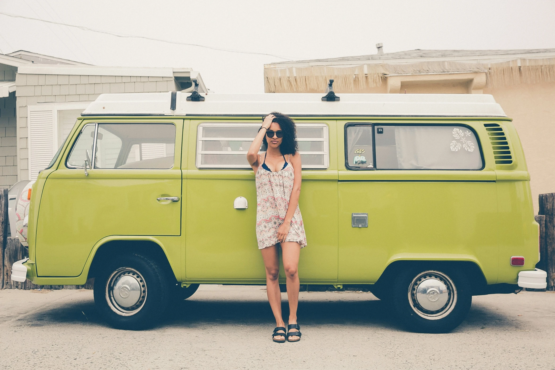 a woman standing next to a green bus on the side of a road