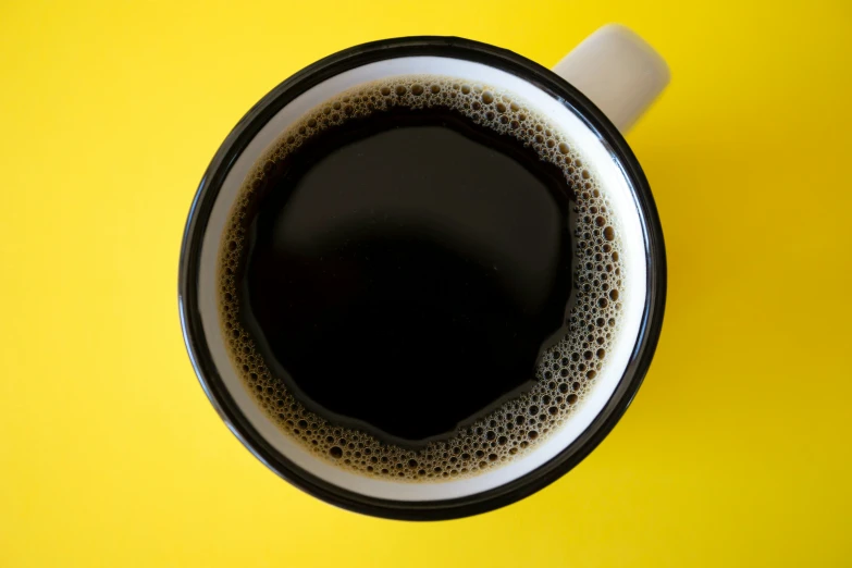 a white cup filled with a liquid on top of a yellow table