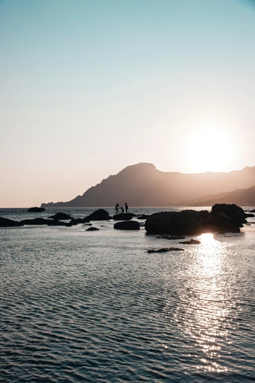 there are rocks in the water and people on the shore