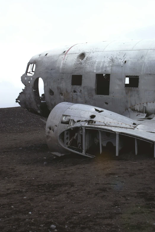 a burned airplane sits on a barren terrain