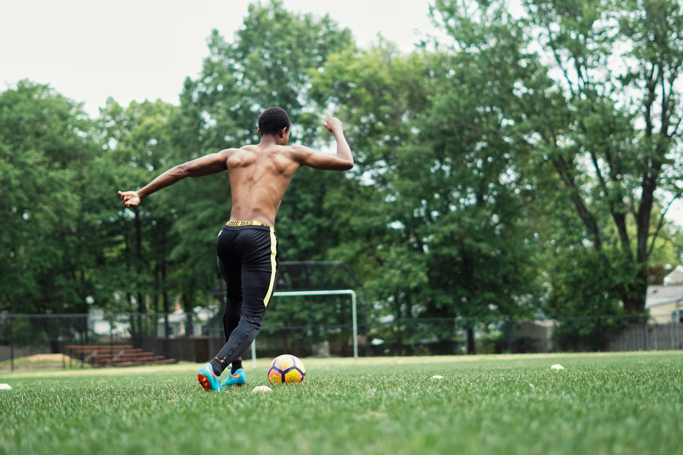 a shirtless man is playing with balls on the field