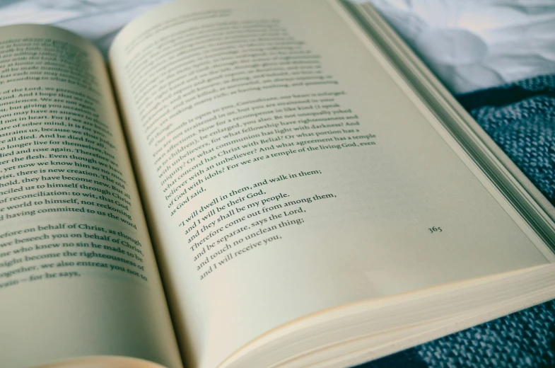 an open book laying on top of a white blanket