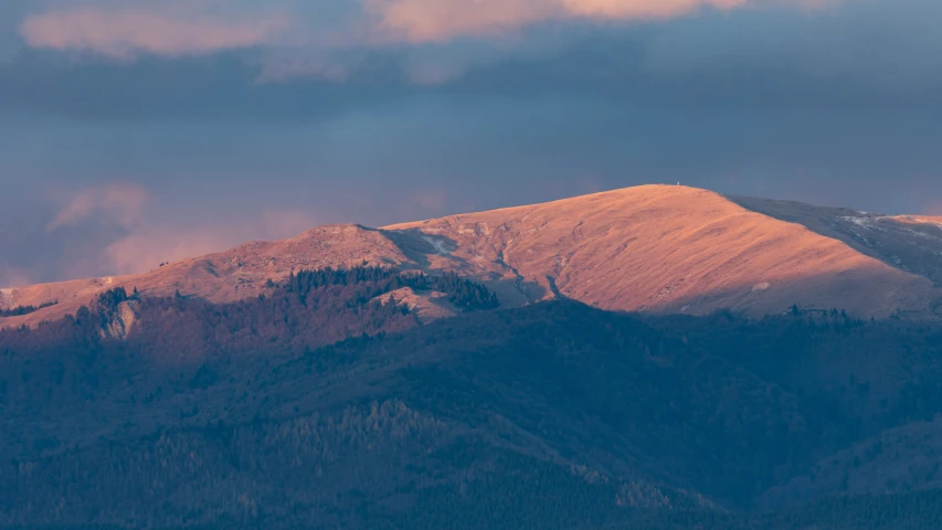 the sun sets over mountains with snow on them