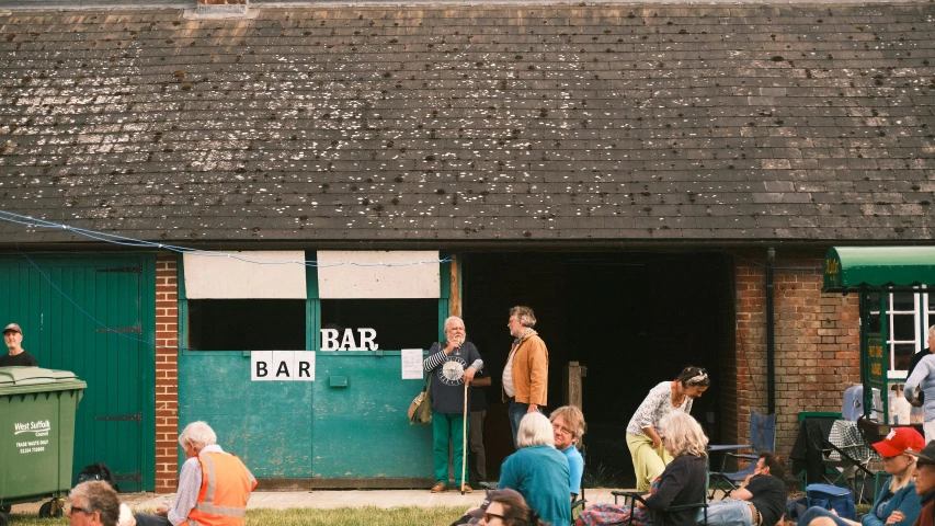 people standing outside a brick bar next to green doors