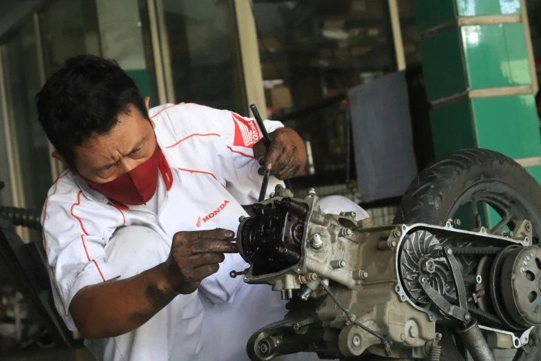 a man in a white shirt and red tie repairing an engine