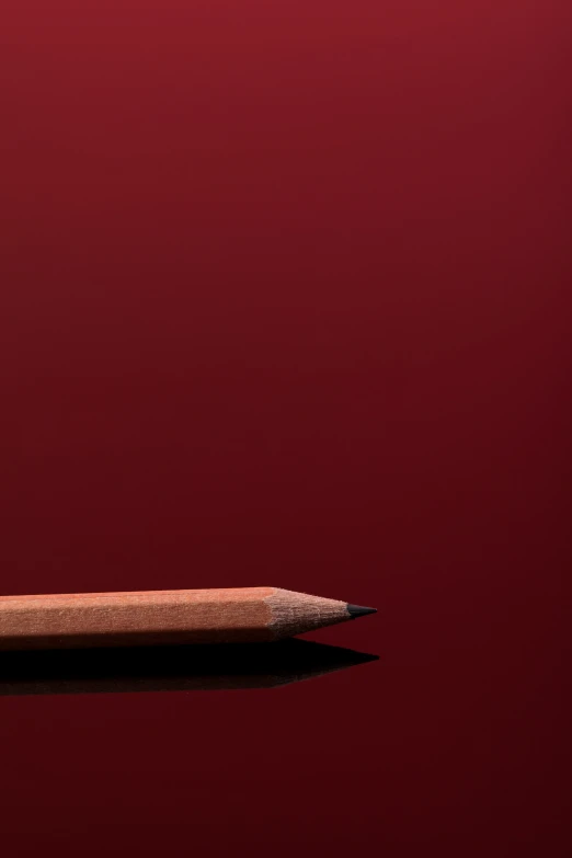 two pencils on a red surface