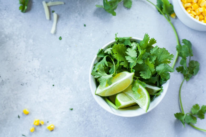 a bowl with green vegetables and some sliced up limes