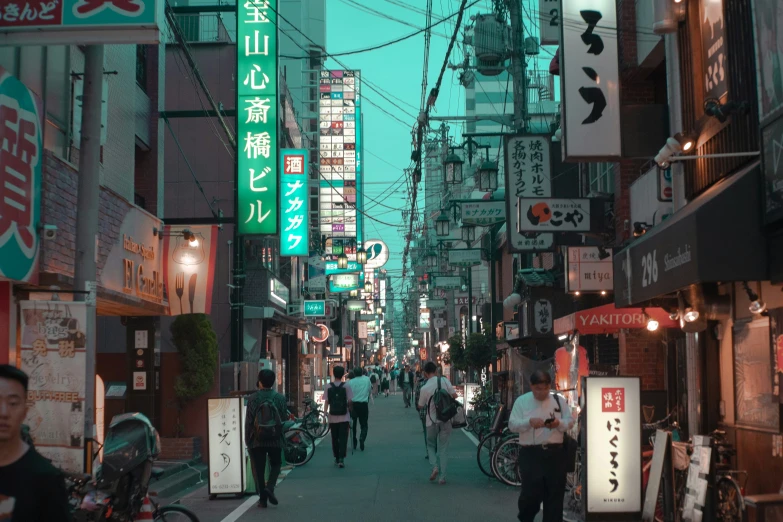 this is an asian city at night with people walking in the distance