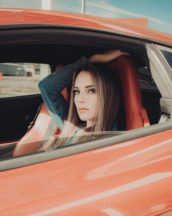 a beautiful young lady sitting in a red car