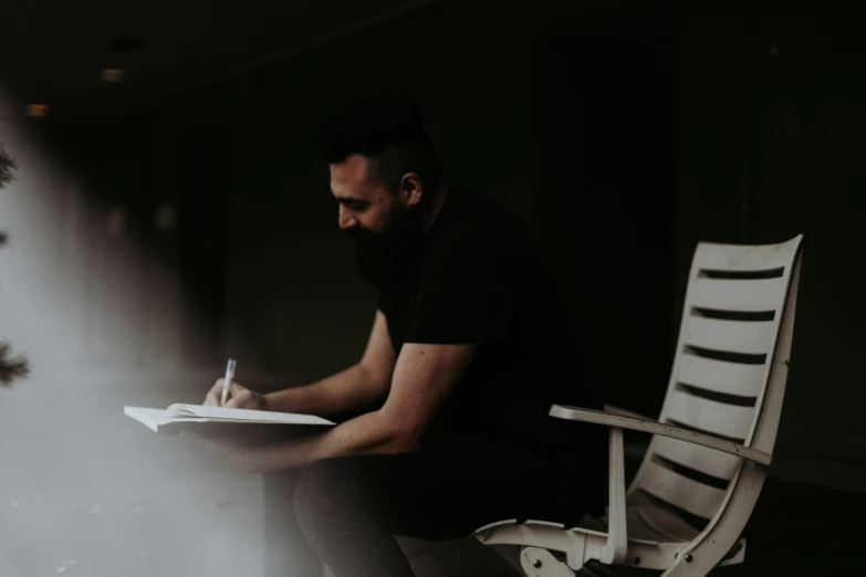 man sitting in the shadows with his hands on a paper